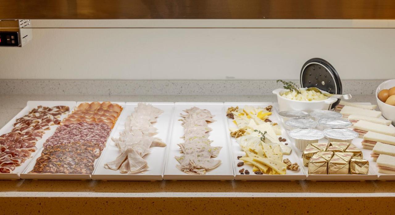 Hotel Ilunion Merida Palace Exterior photo The photo displays a variety of food items arranged on a counter. From left to right, there appears to be several types of sliced meats, possibly including salami and ham. Next, there are slices of a lighter-colored meat, likely turkey or chicken. Fo